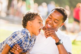 African american father and mixed-race son eating an apple in the park