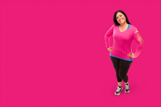 Middle aged hispanic woman in workout clothes against A bright pink background