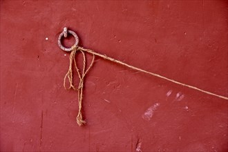 Metal ring on red wall with long cord