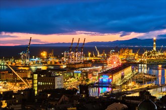 Genoa port illuminated with port cranes and industrial area