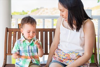 Young chinese mother sitting with her mixed-race chinese and caucasian boy enjoying his ice cream cone