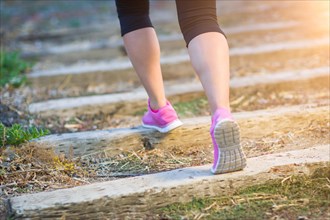 Young fit adult woman outdoors walking or running up wooden steps