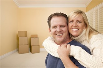 Happy affectionate couple in room of new house with only boxes on the floor