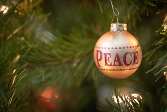 Peace written on christmas ornament hanging on tree