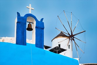 Old traditional whitewashed greek windmill and orthodox christian church bell on Santorini island in Oia town