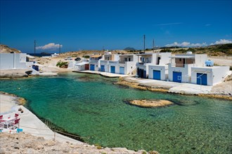 The beach of Agios Konstantinos with crystal clear turquoise water and traditional greek white houses. Milos island