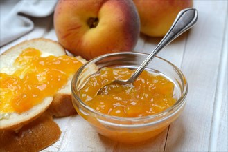 Peach jam in a glass bowl with spoon