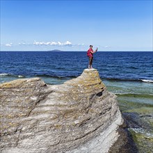 Hiker standing on limestone pillar photographing landscape