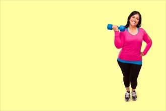 Middle aged hispanic woman in workout clothes holding dumbbell against A bright yellow background