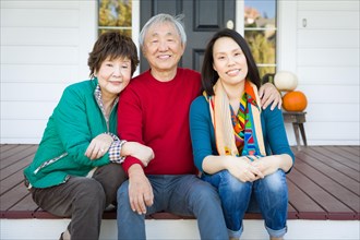 Happy chinese senior adult mother and father with young adult daughter portrait