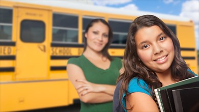 Hispanic mother and daughter near school bus