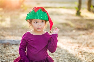 Cute mixed-race young baby girl having fun wearing christmas hat outdoors
