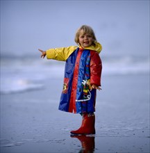 Little girl in mackintosh by the sea Photo: