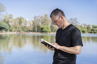 Mature man reading by a lake