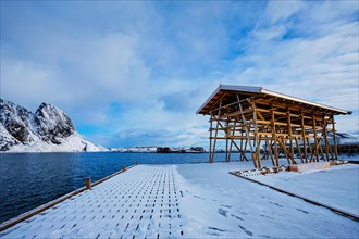 Drying flakes for stockfish cod fish in fjord in winter with snow