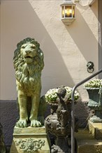 Bronze lion and little angel with flowers in front of facade