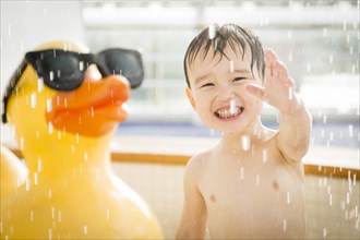 mixed-race boy having fun at the water park with large rubber duck in the background