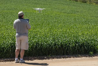 Pilot flying unmanned aircraft drone gathering data over country farmland field