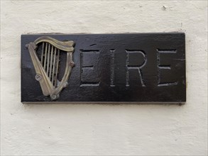 Small wooden sign with Irish harp and lettering Eire on house wall