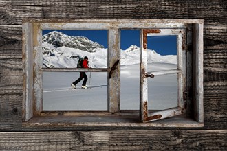 View through a rustic wooden window of a touring skier