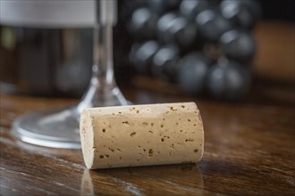 Blank wine cork resting on wood table near grapes