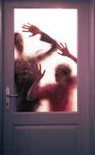Gruselige Silhouette von zwei jungen Erwachsenen im Gegenlicht hinter einer verschlossenen Glastuere