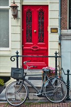 Bicycle near door of old house in Amsterdam street. Bicycles are the very popular means of transport in Netherlands. Amsterdam