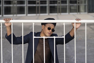 Latin gay male with makeup wearing fashion hat posing in the street