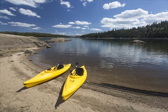 Pair of yellow kayaks on a beautiful mountain lake shore