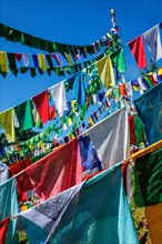 Buddhist prayer flags lungta with Om Mani Padme Hum Buddhist mantra prayer meaning Praise to the Jewel in the Lotus on kora around Tsuglagkhang complex