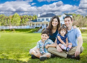 Happy young family with children outdoors in front of beautiful custom home