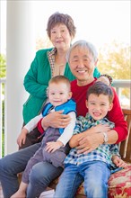 Senior adult chinese couple sitting with their mixed-race grandchildren