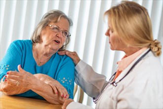 Senior adult woman talking with female doctor about sore arm