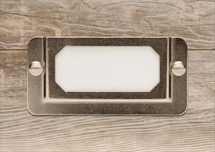 Blank metal file cabinet label frame on wood ready for your own message