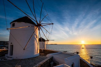 Scenic view of famous Mykonos town windmills. Traditional greek windmills on Mykonos island on sunset with dramatic sky