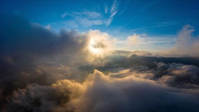 Aerial view above the clouds with the sun shining through the clouds