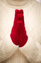 Woman wearing red mittens with hands praying