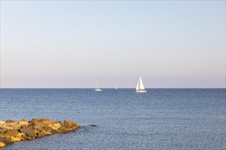 Rocky coast with sailboat in San Lorenzo al Mare
