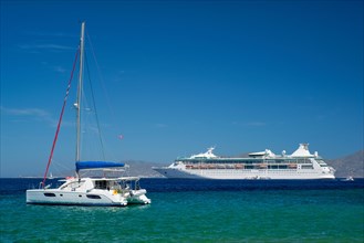 Catamaran yacht and cruise liner is Aegean sea on beautiful summer day. Chora