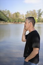 Mature businessman talking on cell phone at a lake