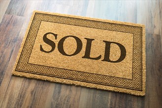 Sold welcome mat on A wood floor background