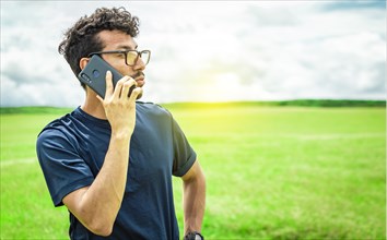 Person with his cell phone in the field calling on the phone