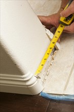 Contractor measuring for new baseboard with bull nose corners and new laminate flooring abstract