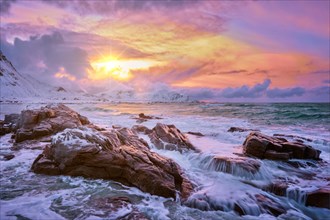 Waves of Norwegian sea on rocky coast in fjord on sunset with sun