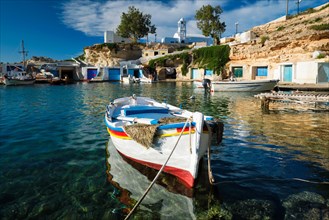 Fishing boats moored in crystal clear turquoise sea water in harbour in Greek fishing village of Mandrakia