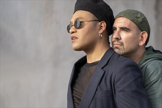 Gay latin couple wearing fashionable hats hugging in the street. Copy space