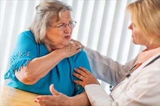 Senior adult woman talking with female doctor about sore shoulder