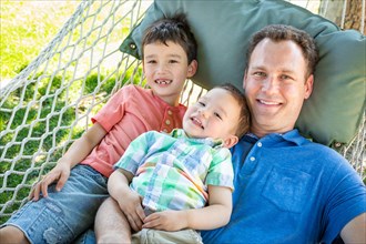 Caucasian father relaxing in hammock with mixed-race chinese sons
