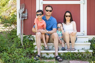 Portrait of caucasian and chinese couple with their mixed-race young boys wearing sunglasses