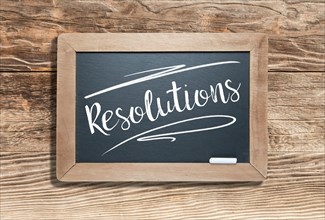 Resolutions written on slate chalk board against aged wood background